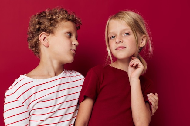 Portret van schattige kinderen emoties staan naast elkaar in alledaagse kleding rode achtergrond