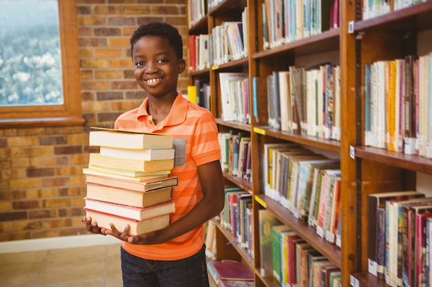 Portret van schattige kleine jongen die boeken in de bibliotheek