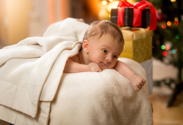 Portret van schattige pasgeboren baby liggend op de buik naast kerstcadeaus