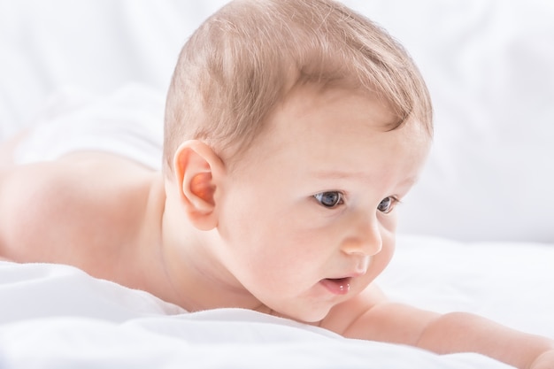 Portret van schattige peuter jongen liggend op bed. Pasgeboren kind in de slaapkamer.