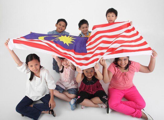 Foto portret van schattige vrienden met de maleisische vlag op een witte achtergrond