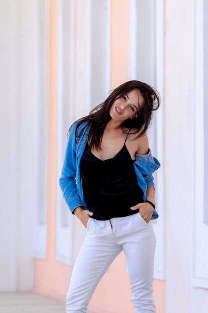 Portret van schattige vrolijke lachende jonge mooie vrouw in casual jeans kleding. staande op lichte zaal achtergrond.