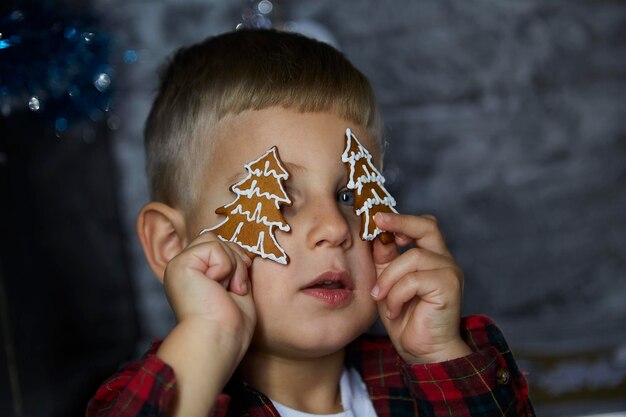 Portret van schattige vrolijke peuter Kleine jongen speelt met kerstkoekjes tussen feestelijke decoraties Sfeervol huis voor oudejaarsavond 39s Esthetisch gezellig huis Vrolijke babyjongen Vrolijk concept