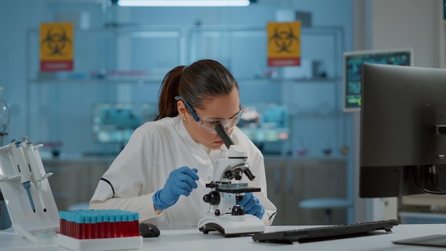 Portret van scheikundige die met Microscoop in laboratorium werkt, om wetenschappelijk experiment te ontwikkelen. Microbiologiespecialist die optisch hulpmiddel met microscopische lens gebruikt om dna-monster in laboratorium te analyseren.