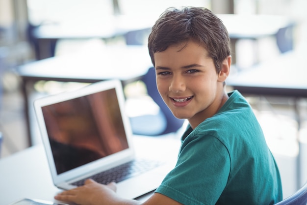 Portret van schooljongen die laptop in klaslokaal met behulp van