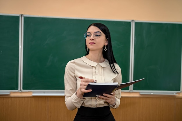 Portret van schoolleraar draagt witte blouse en bril in de buurt van op de achtergrond van het bord