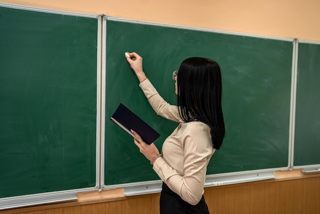 Portret van schoolleraar draagt witte blouse en bril in de buurt van op de achtergrond van het bord
