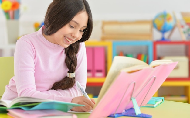 Portret van schoolmeisje dat huiswerk doet in haar kamer