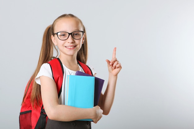 Portret van schoolmeisje met een rugzak en briefpapier