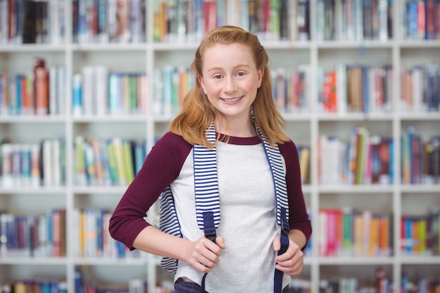 Portret van schoolmeisje permanent met Schooltasje in bibliotheek