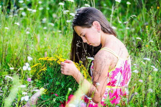 Portret van schoolmeisje tussen de bloemen in de zomer