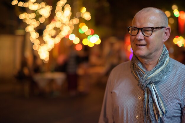 Portret van senior knappe Scandinavische toeristenmens die de straten van de stad 's nachts verkennen