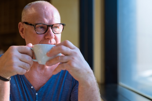 Portret van senior knappe scandinavische toeristische man ontspannen in de coffeeshop