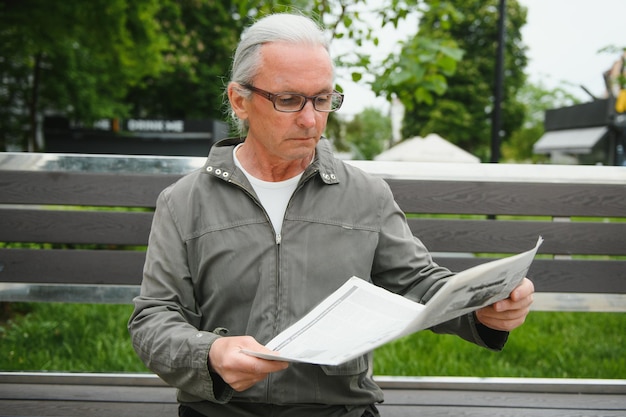 Portret van senior man lezen op bankje tijdens zomerdag