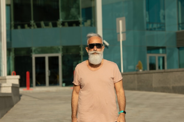 Portret van senior man met casual kleding wegkijken. Volwassen man met baard straat lopen op een zomerdag.