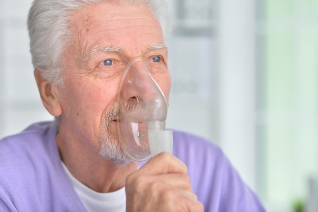 Portret van senior man met inhalator thuis