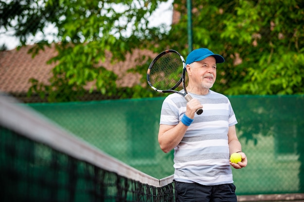 Portret van senior man tennissen in een buiten, gepensioneerde sport, sport concept