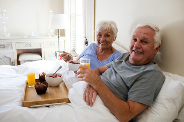 Portret van senior paar ontbijten in de slaapkamer thuis