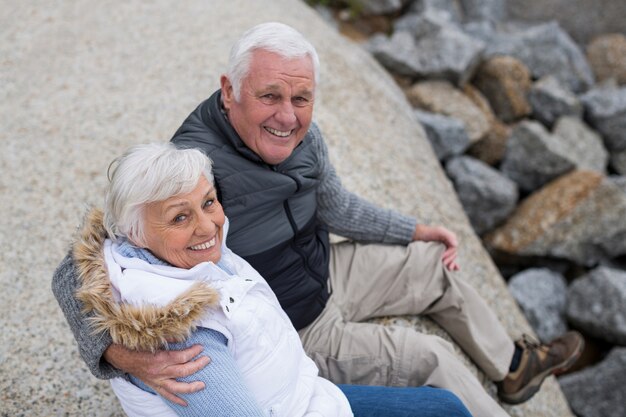 Portret van senior paar zittend op rots op het strand