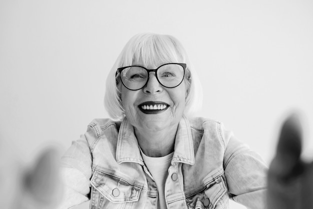 portret van senior stijlvolle vrouw met grijs haar en in spijkerjasje die je knuffelt of selfie maakt