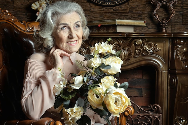 Portret van senior vrouw met bloemen thuis