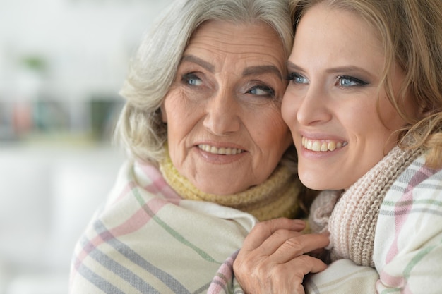 Foto portret van senior vrouw met dochter die bedekt met deken