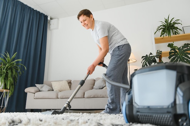 Portret van senior vrouw met stofzuiger binnenshuis thuis stofzuigen