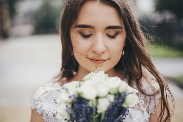 Portret van sensuele bruid met bruidsboeket van rozen en lavendel in stijlvolle jurk Provençaalse bruiloft Mooie bruid in stijlvolle vintage jurk poseren in zonnige straat van Europese stad