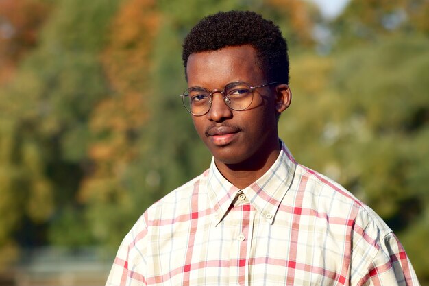 Portret van serieuze knappe zwarte Afro-Amerikaanse aantrekkelijke kerelstudent in bril en shirt