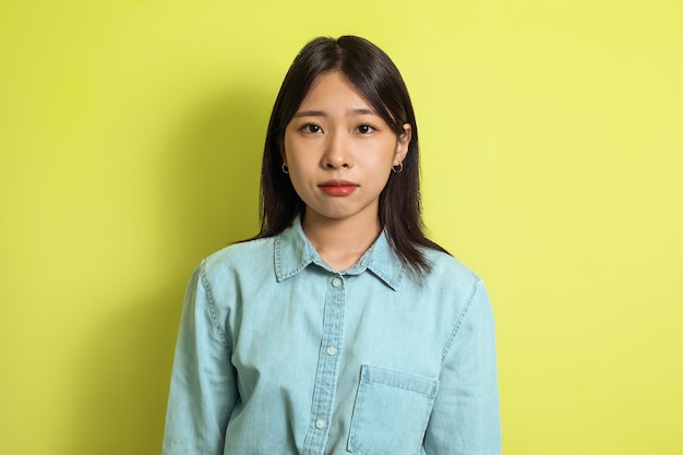 Portret van serieuze Koreaanse vrouw die zich voordeed op gele achtergrond
