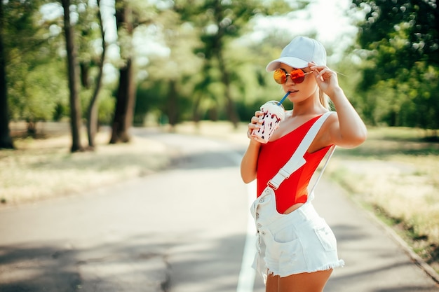 Portret van sexy stijlvolle mode meisje met afgeronde zonnebril rode zwembroek witte baseball cap sho...