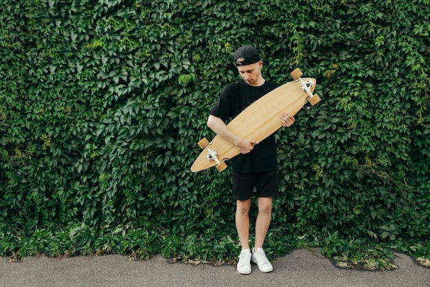 Portret van skateboarder met bord in handen op groene achtergrond