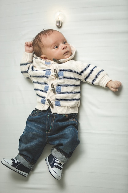 portret van slimme babyjongen met gloeiende gloeilamp boven je hoofd