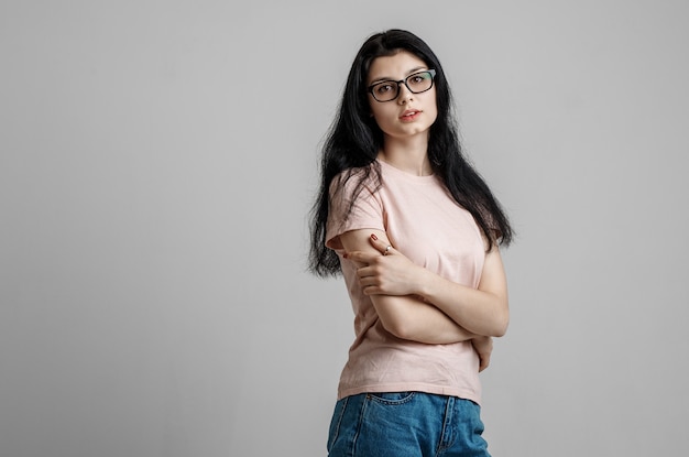 Portret van slimme mooie brunette meisje in brillen met natuurlijke make-up, op grijze achtergrond.