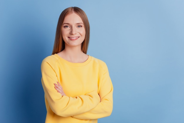 Portret van slimme succesvolle zakendame gevouwen handen glanzende glimlach op blauwe achtergrond