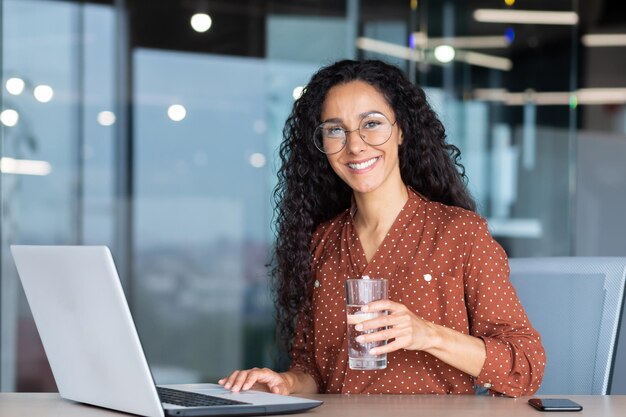 Portret van Spaanse vrouw binnen moderne kantoor op het werk zakenvrouw glimlachend en camera kijken