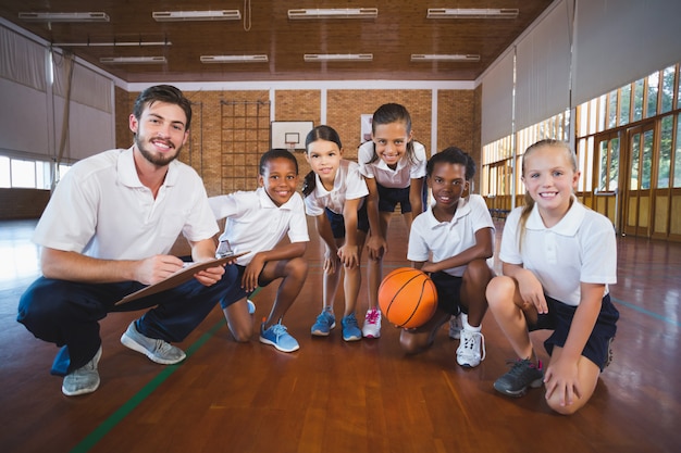 Portret van sportleraar en schoolkinderen in basketbalveld