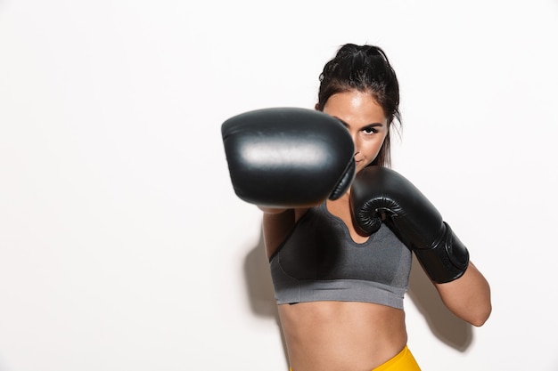 Portret van sterke geconcentreerde prachtige jonge sport fitness vrouw bokser geïsoleerd over witte muur muur maken boksoefeningen met handschoenen.