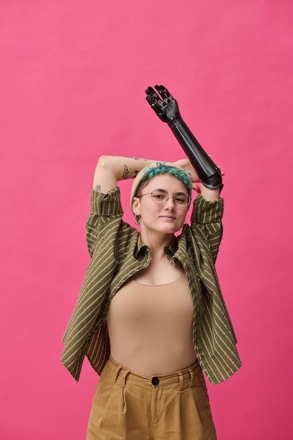 Portret van stijlvol jong meisje met prothese poseren op camera tegen roze achtergrond