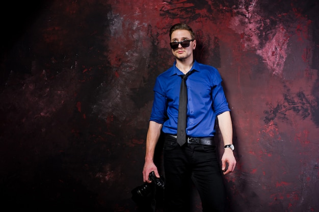 portret van stijlvolle professionele fotograaf man met camera, draag op blauw shirt en stropdas, zonnebril.