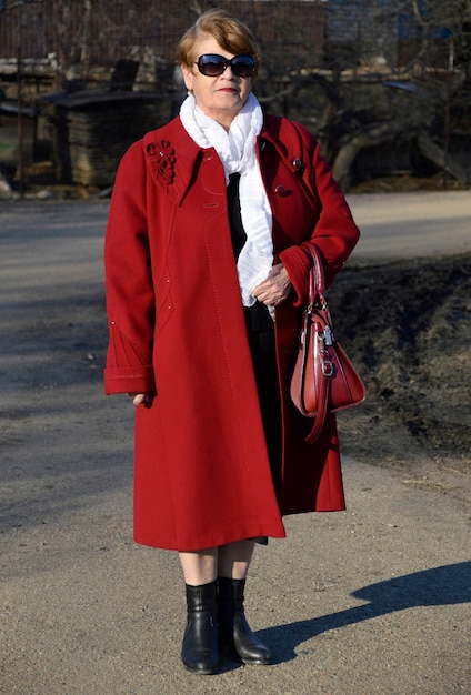 Foto portret van stijlvolle senior vrouw, gekleed in een rode jas