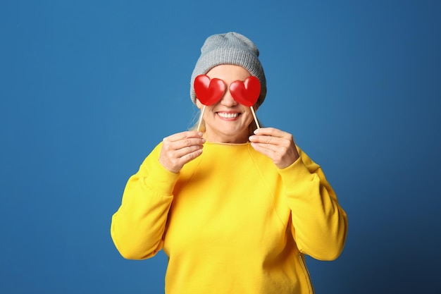 Portret van stijlvolle vrouwelijke gepensioneerde m/v met lolly's op kleur achtergrond