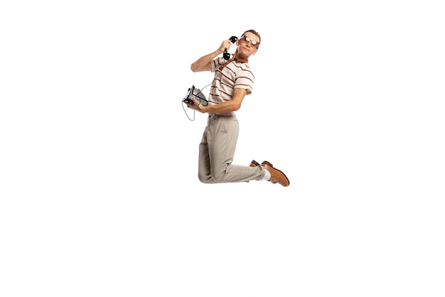 Portret van stijlvolle zakenman in retro kleding schreeuwen op vintage telefoon in een sprong geïsoleerd over