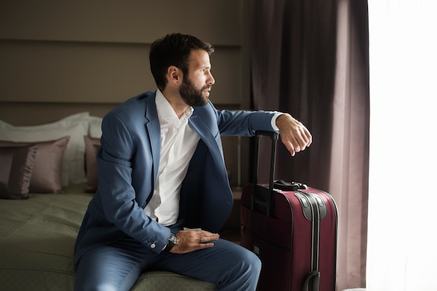 Portret van succesvolle jonge zakenman die in hotelkamer zit