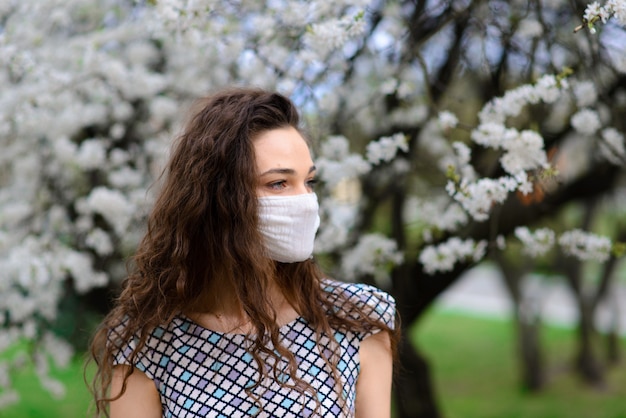 Portret van tedere vrouw onder een bloeiende boom met een masker close-up