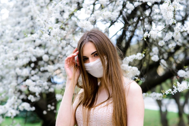 Portret van tedere vrouw onder een bloeiende boom met een masker close-up