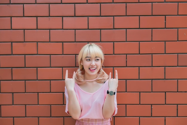 Portret van Thaise vrouw met gouden haren in japanse stijl op oranje bakstenen muur Aziatisch meisje poseert voor het maken van een foto buiten