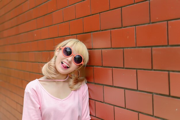 Foto portret van thaise vrouw met gouden haren in japanse stijl op oranje bakstenen muur aziatisch meisje poseert voor het maken van een foto buiten