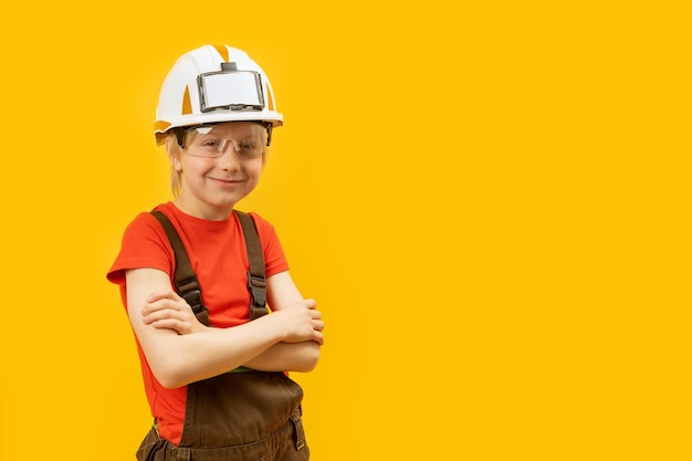 Portret van tiener draagt beschermende helmbril en jumpsuit als arbeider of bouwvakker op gele achtergrond Kopieer ruimte