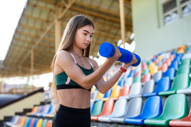 Portret van tiener fitness meisje doen oefening met halter in het stadion. .